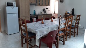 Cocina pequeña con refrigerador, armarios de madera y una mesa de comedor con sillas.
