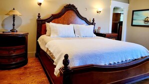 A bedroom with a wooden bed, two bedside lamps, and a nightstand. - Vintage Poulsbo Apartment with Bay views (Poulsbo)
