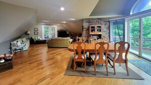 A spacious living area with a dining table, wooden chairs, and a stone fireplace. - Vintage Poulsbo Apartment with Bay views (Poulsbo)
