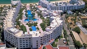 A resort with a central pool, multiple buildings, and a beach.