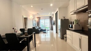 A modern kitchen with a refrigerator, microwave, and a dining area with a table and chairs.