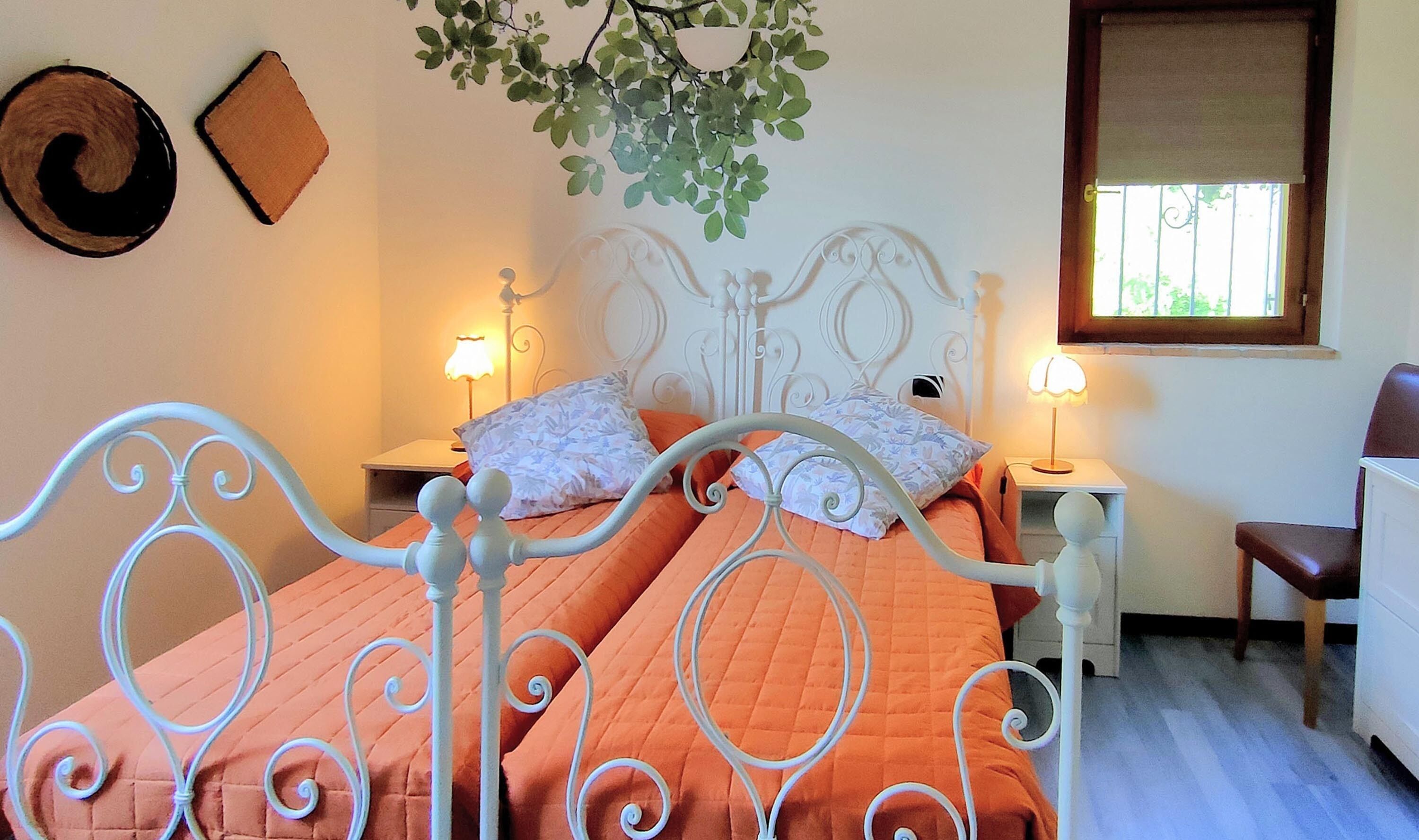 Une chambre avec un lit, deux lampes de chevet, une fenêtre et une plante fixée au mur.