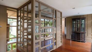 A room with wooden flooring, a glass partition, and a dark wooden cabinet.