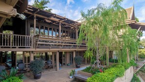 A two-story building with a balcony, outdoor seating area, and potted plants. - Syama Residence (Ayutthaya)
