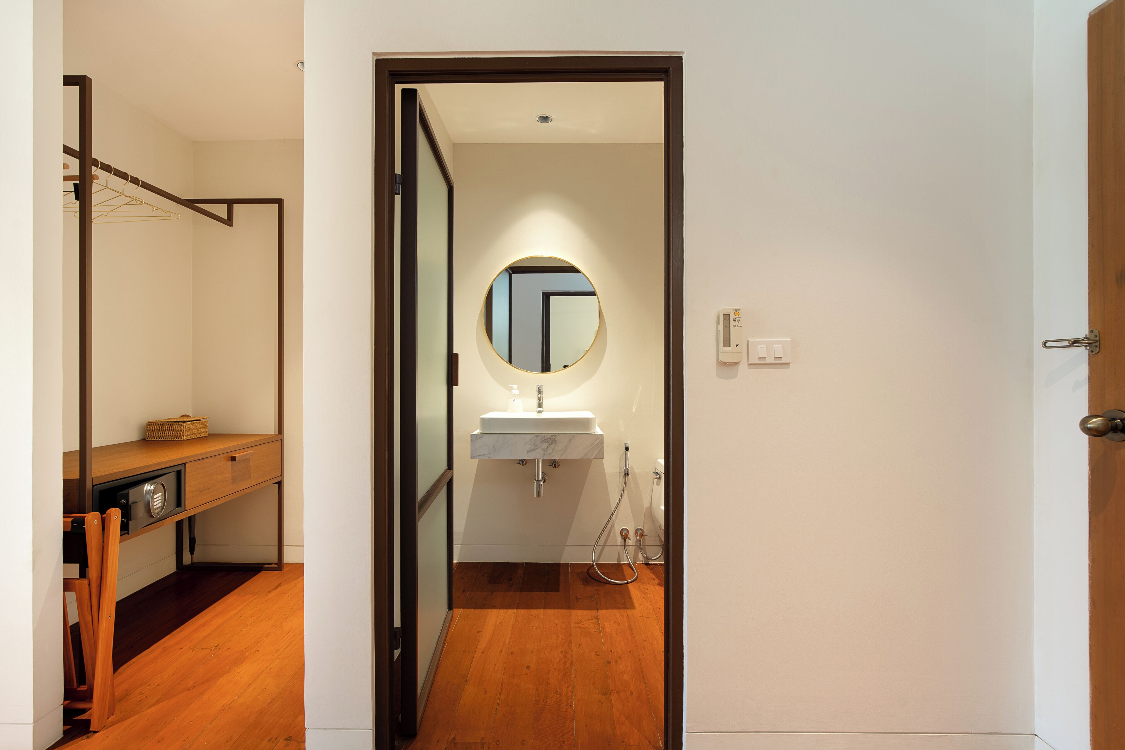 Un baño moderno con suelo de madera, un lavabo blanco y un espejo.