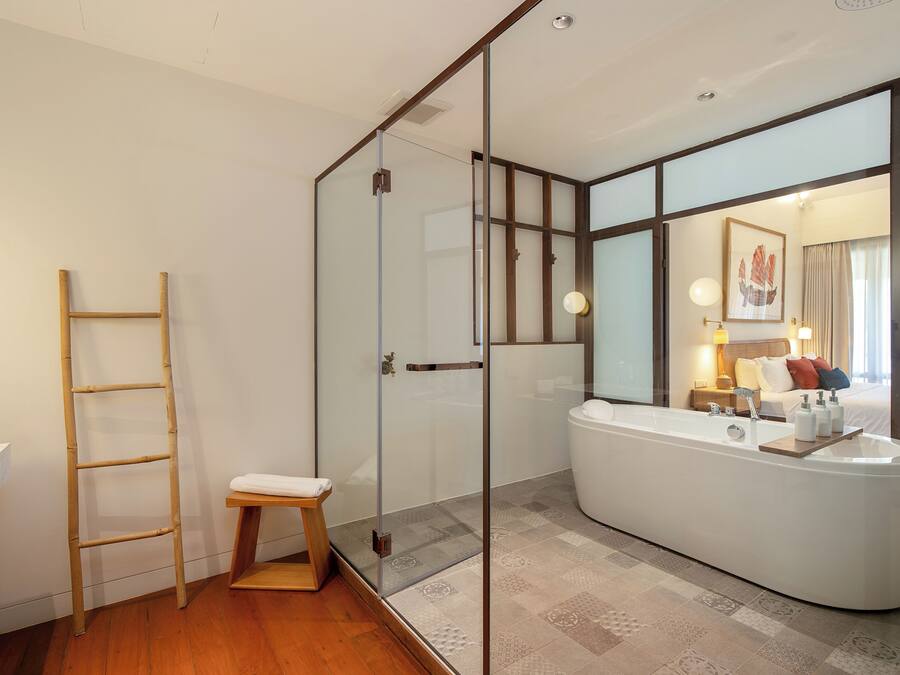 A modern bathroom with a glass shower enclosure, a freestanding bathtub, and a wooden ladder.