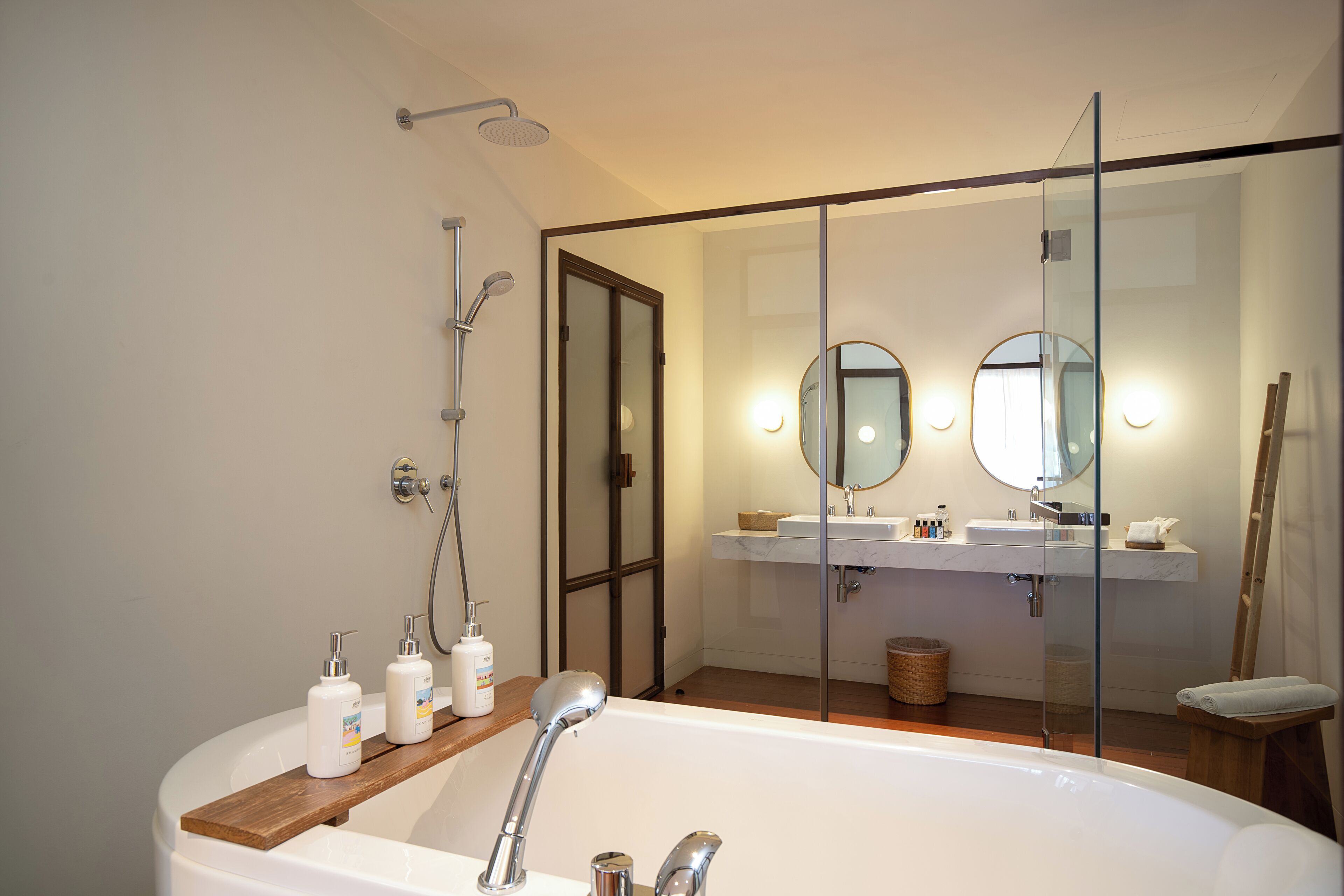 A modern bathroom with a freestanding bathtub, a glass-enclosed shower area, and a vanity with a mirror and sink.