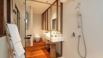 Un baño moderno con cabina de ducha de vidrio, suelo de madera y lavamanos blanco.