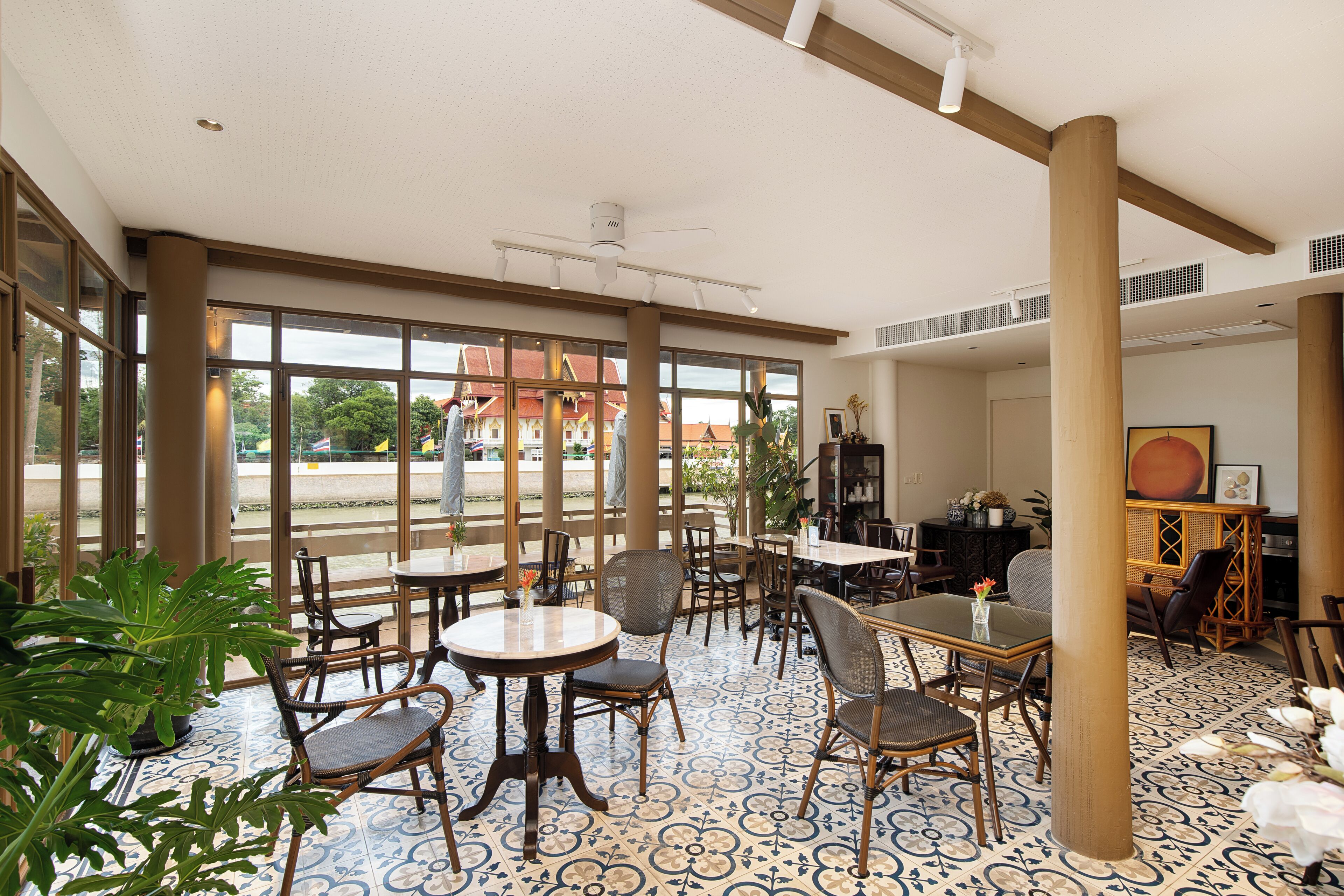 Un vaste espace intérieur doté de grandes fenêtres, de meubles en bois et d’un sol à motifs.