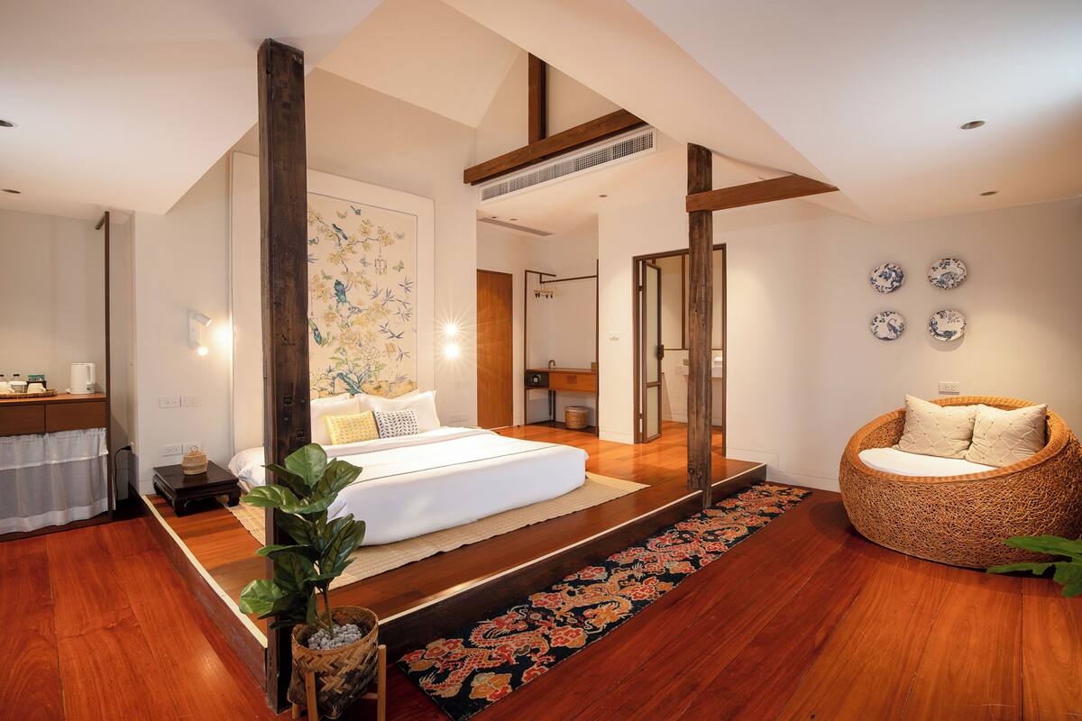 Un dormitorio moderno con una cama grande, una zona de estar y una pared decorativa.