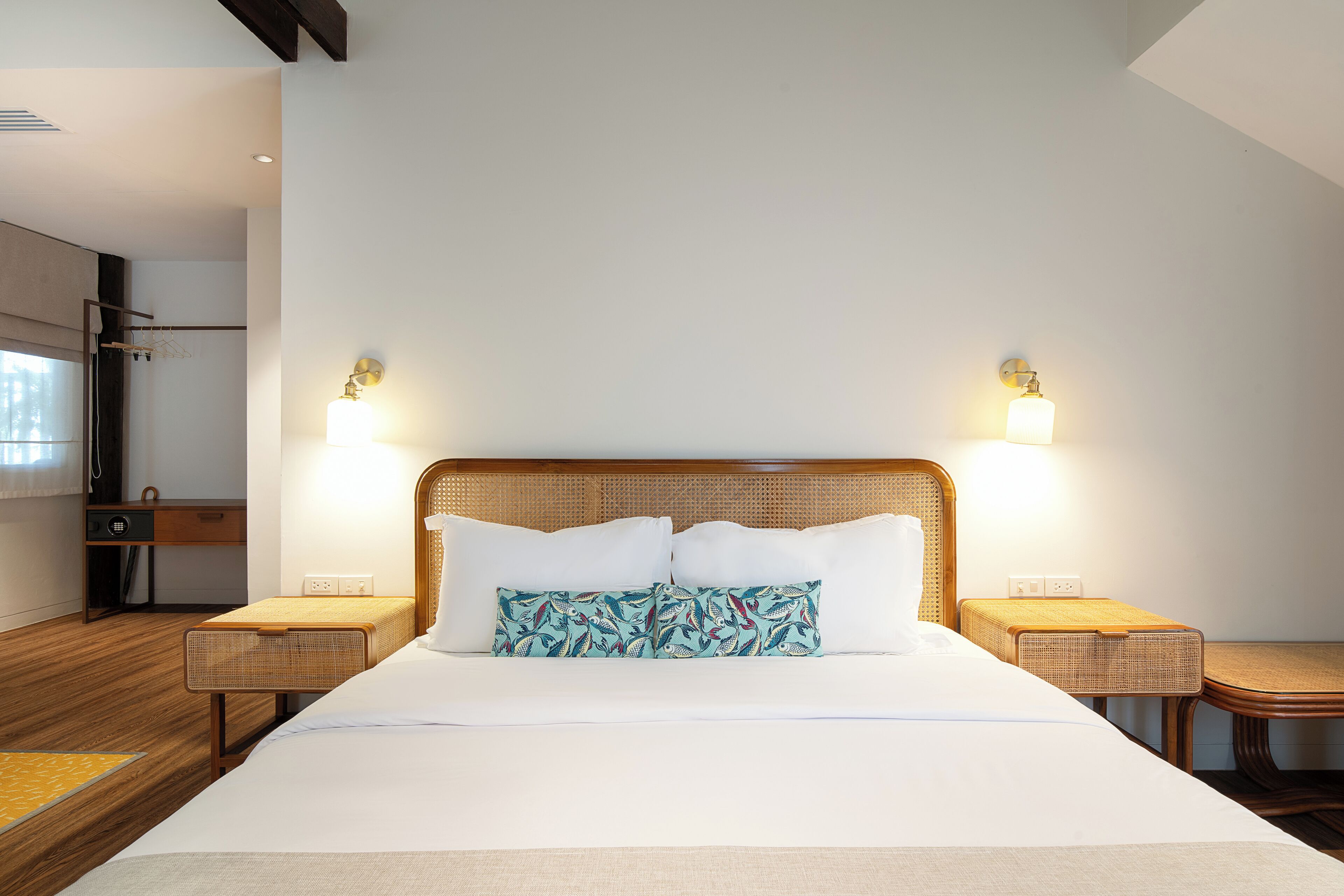 Quarto de hotel moderno com uma cama grande, duas mesas de cabeceira e cabeceira com iluminação integrada.