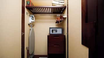 A compact room with a built-in ironing board, a microwave, and a small wooden cabinet.