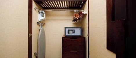 A compact room with a built-in ironing board, a microwave, and a small wooden cabinet.