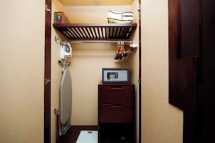 Una habitación compacta con plancha integrada, microondas y un pequeño armario de madera.