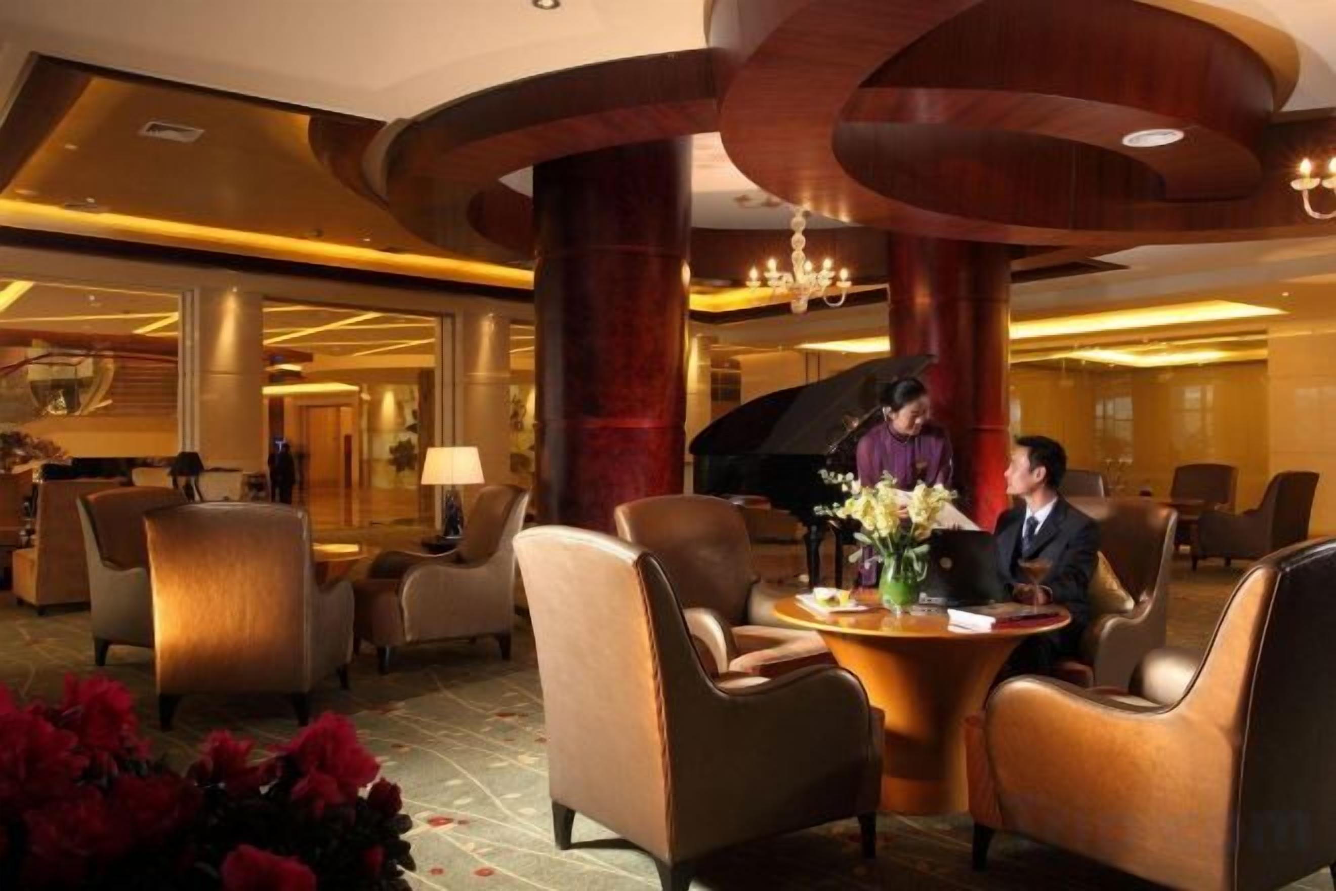 A lobby with seating arrangements, a piano, and a reception desk.
