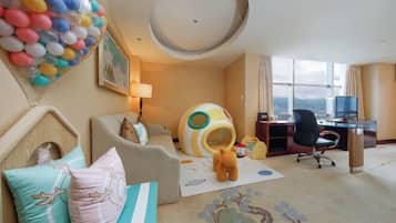 Hotelkamer met een bed, bureau, stoel, raam met uitzicht en kleurrijke ballondecoratie.