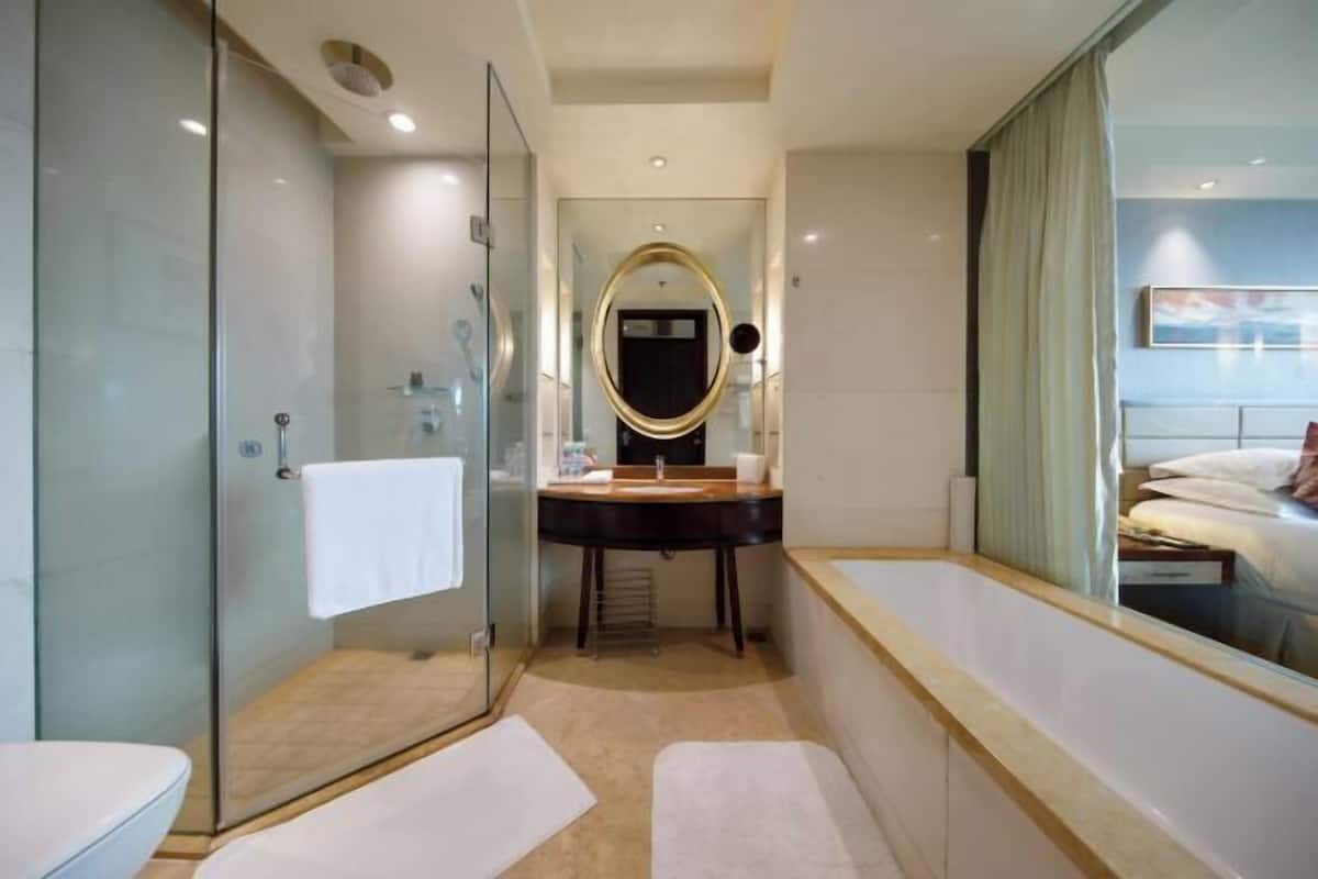 A modern bathroom with a glass shower enclosure, a vanity with a mirror, and a bathtub.