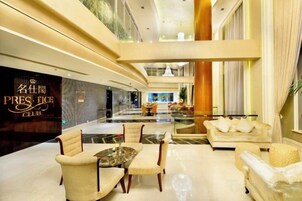 Un hall de hotel con mostrador de recepción, zona de estar y vistas al interior.