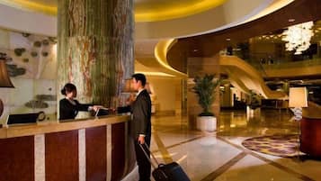 A hotel reception area with a marble column, a reception desk, and a modern interior design.