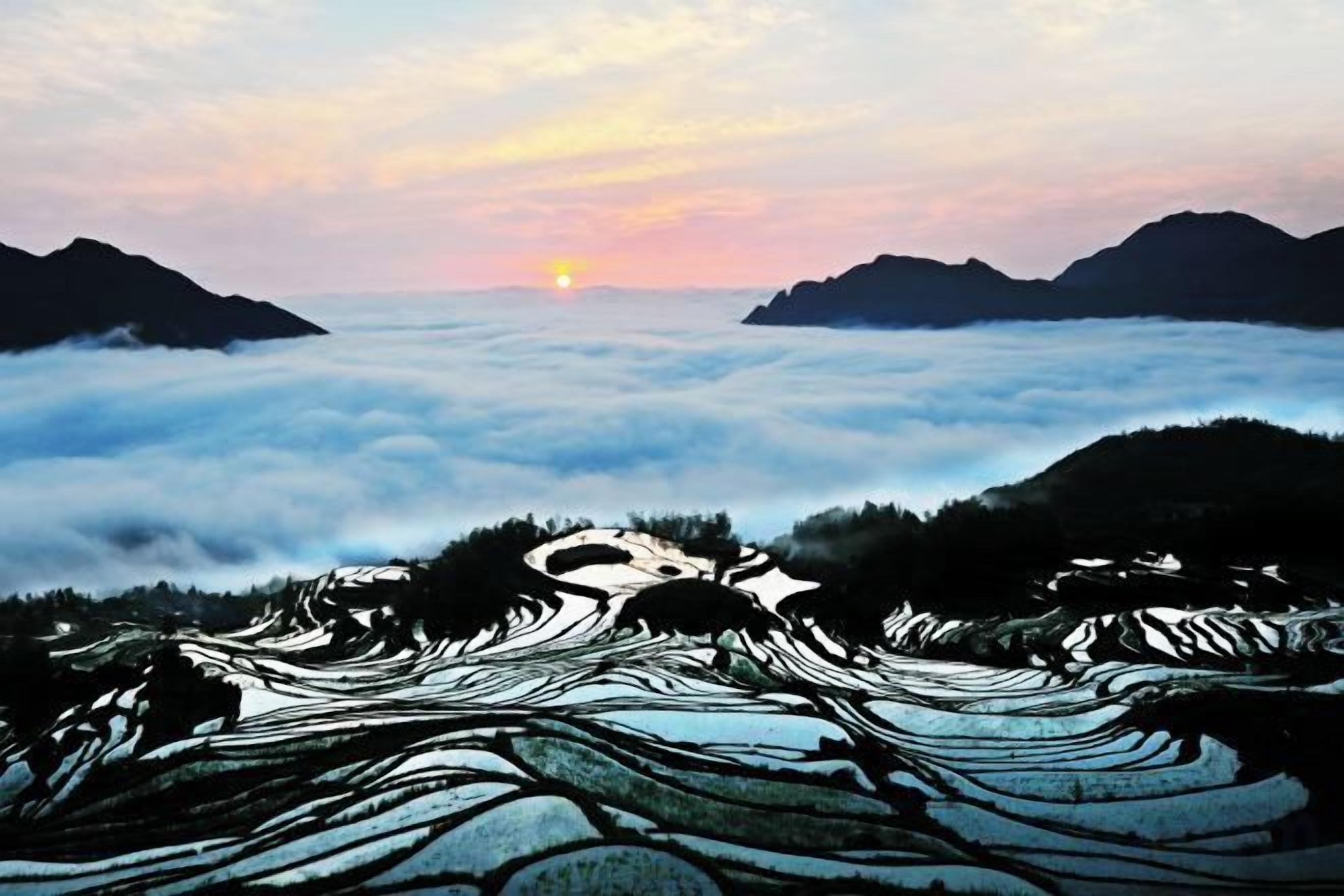 A landscape with terraced fields and a sunrise or sunset.