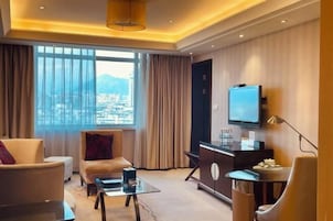 Habitación de hotel moderna con un ventanal grande, televisión de pantalla plana, escritorio y sofá.