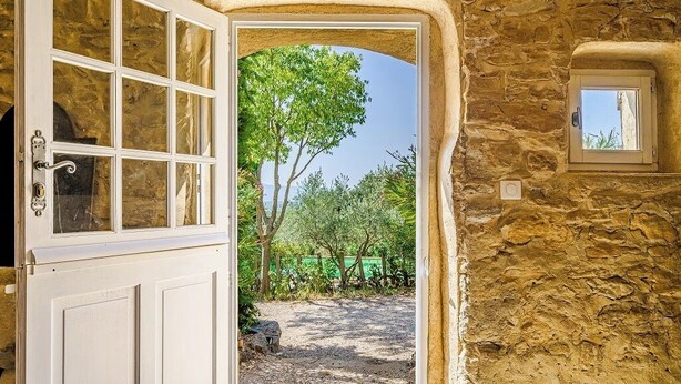 A rustic stone doorway leading to a garden with a tree and a small window. - Domaine Clément Sainte Victoire, 7ha of tranquility 17 km from Aix (Puyloubier)