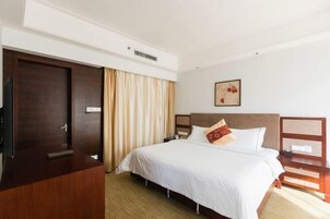 Una habitación de hotel con cama, armario, televisor y un cuadro en la pared.
