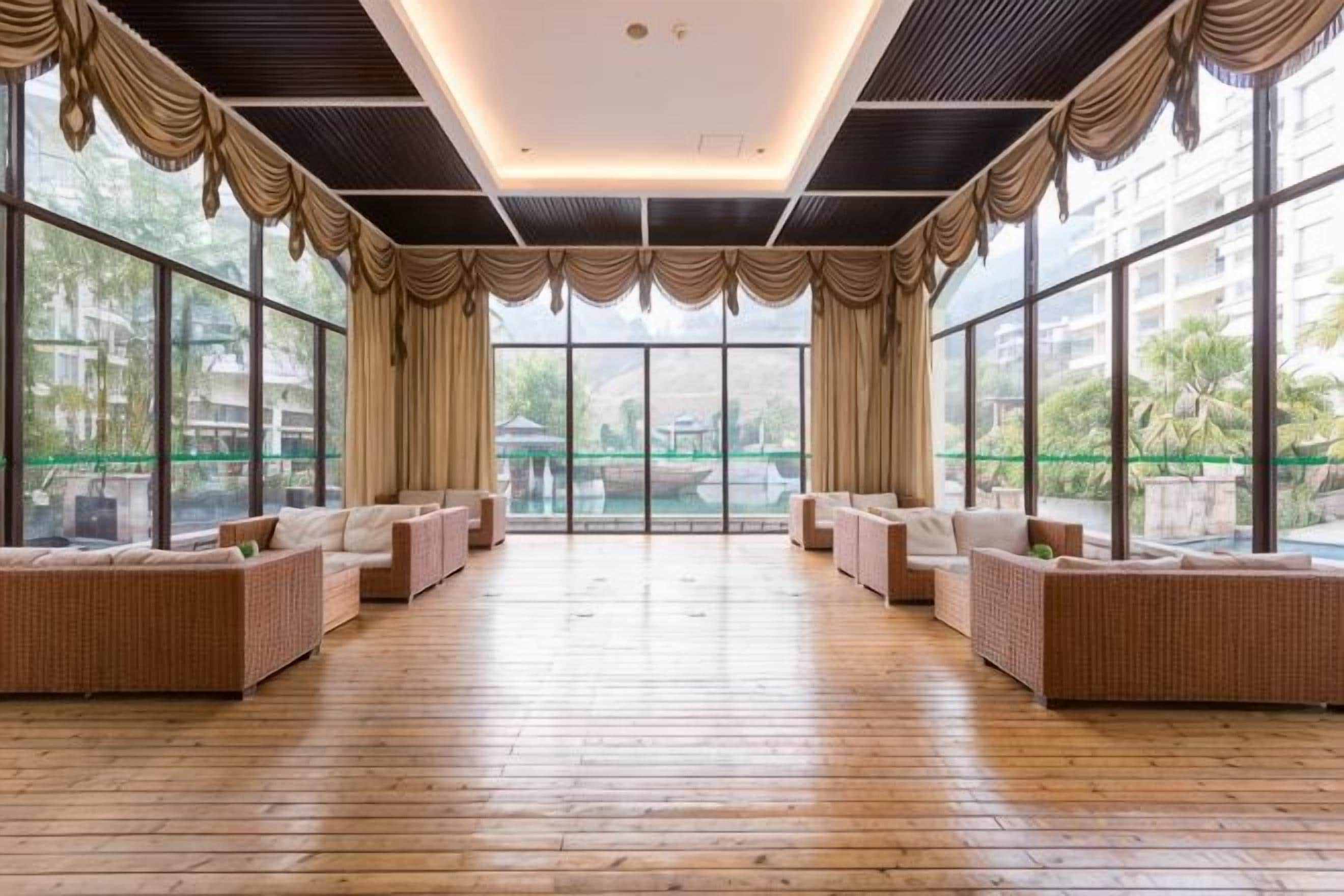 Una habitación amplia con suelo de madera, ventanas grandes y vistas a zonas verdes.