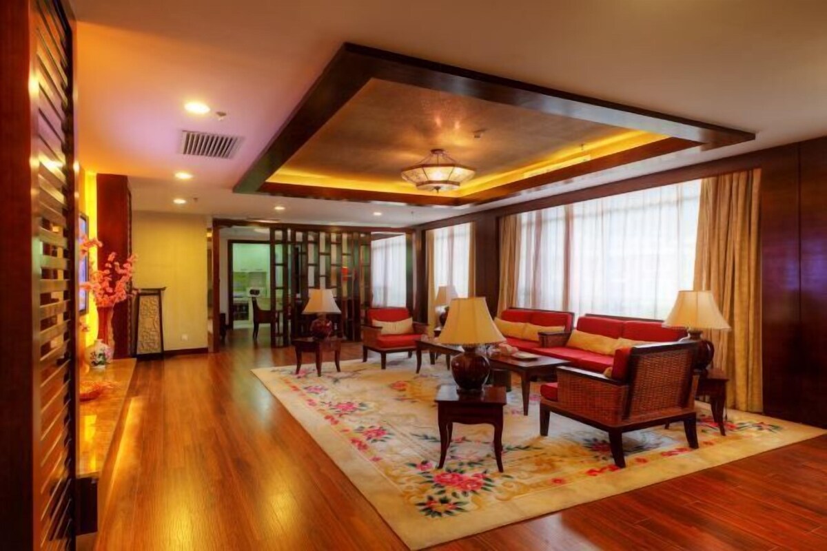 A hotel lobby with a wooden floor, a sofa set, and a decorative rug.