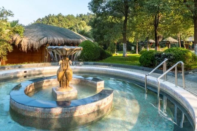 A circular pool with a central fountain, surrounded by a paved walkway.