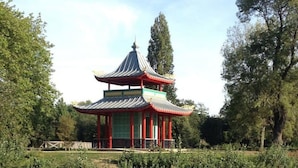 Un pavillon traditionnel à plusieurs niveaux, dont l’image se reflète dans l’eau, et qui est entouré de verdure.
