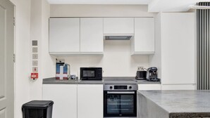 Une cuisine moderne avec des meubles blancs, un four à micro-ondes, une machine à café et un four traditionnel.