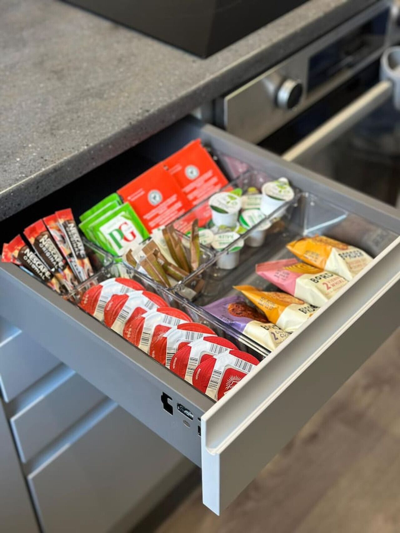 Un cajón de cocina con diversos alimentos, incluyendo aperitivos envasados, condimentos y productos lácteos.