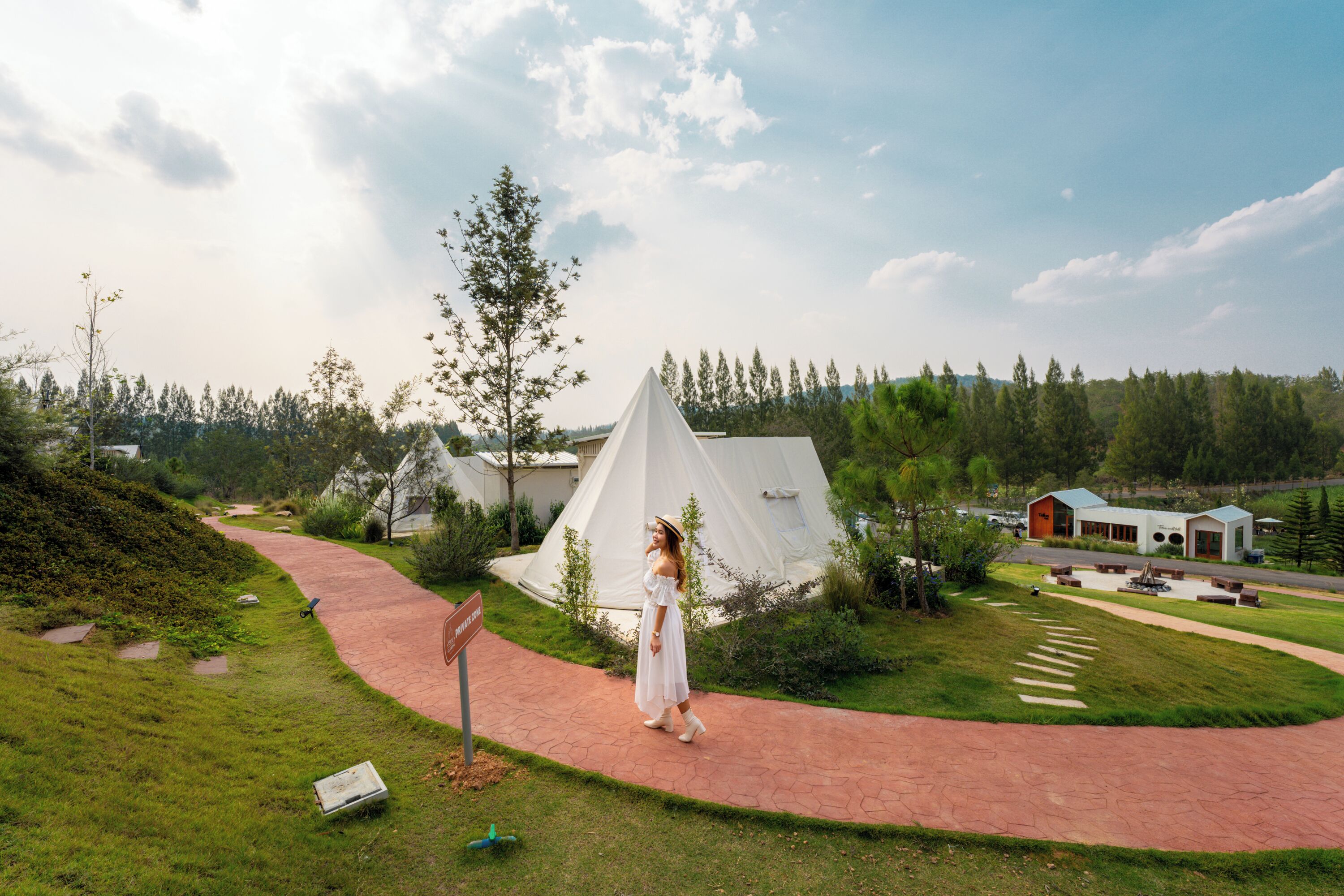 A campsite with tents, a paved path, and a grassy area.