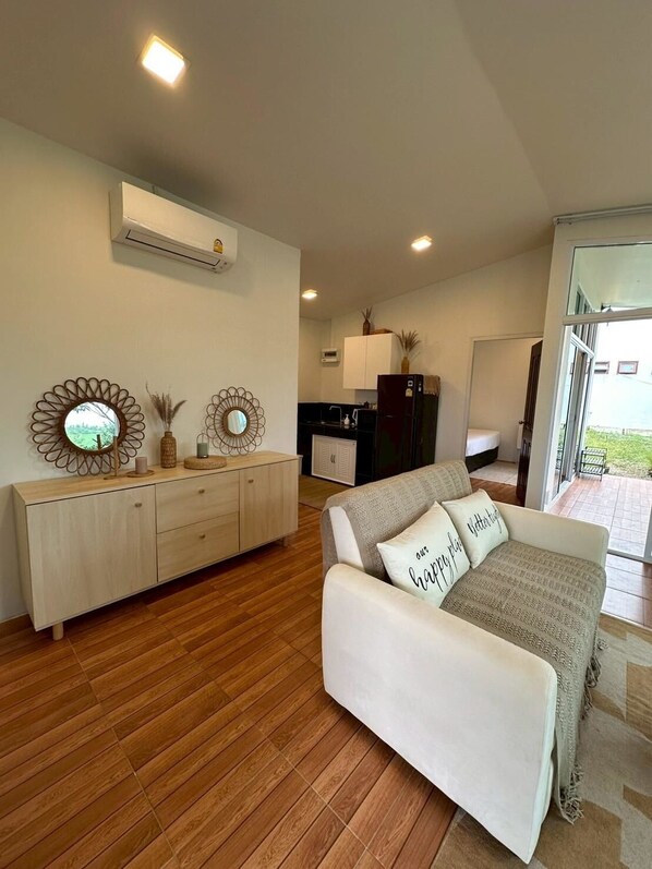Una sala de estar moderna con un sofá, un mueble de madera y espejos decorativos.