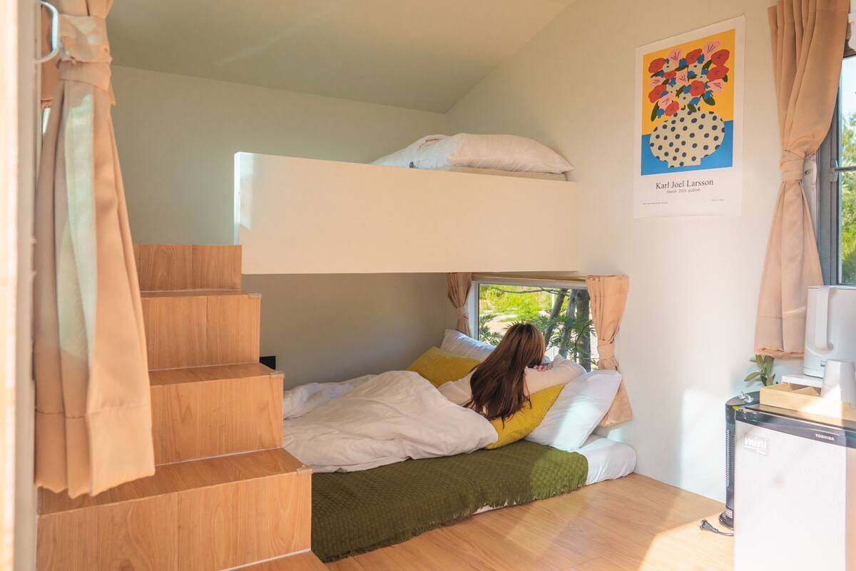 Une chambre avec un lit superposé, une fenêtre, une affiche au mur et un petit bureau avec un ordinateur.