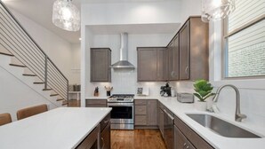 A modern kitchen with stainless steel appliances, wooden cabinets, and pendant lighting. - West End- Best for Families, Work & College Visits (Nashville)