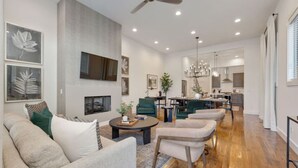 A spacious living room with a fireplace, modern furniture, and a dining area with a kitchen in the background. - West End- Best for Families, Work & College Visits (Nashville)