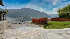 A stone pathway leading to a waterfront with a mountain backdrop.