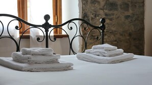 A neatly made bed with folded white towels and a metal headboard.