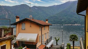 A coastal building with a balcony overlooking a lake, surrounded by mountains. - Piazza Campidoglio 5 (Tremezzina)