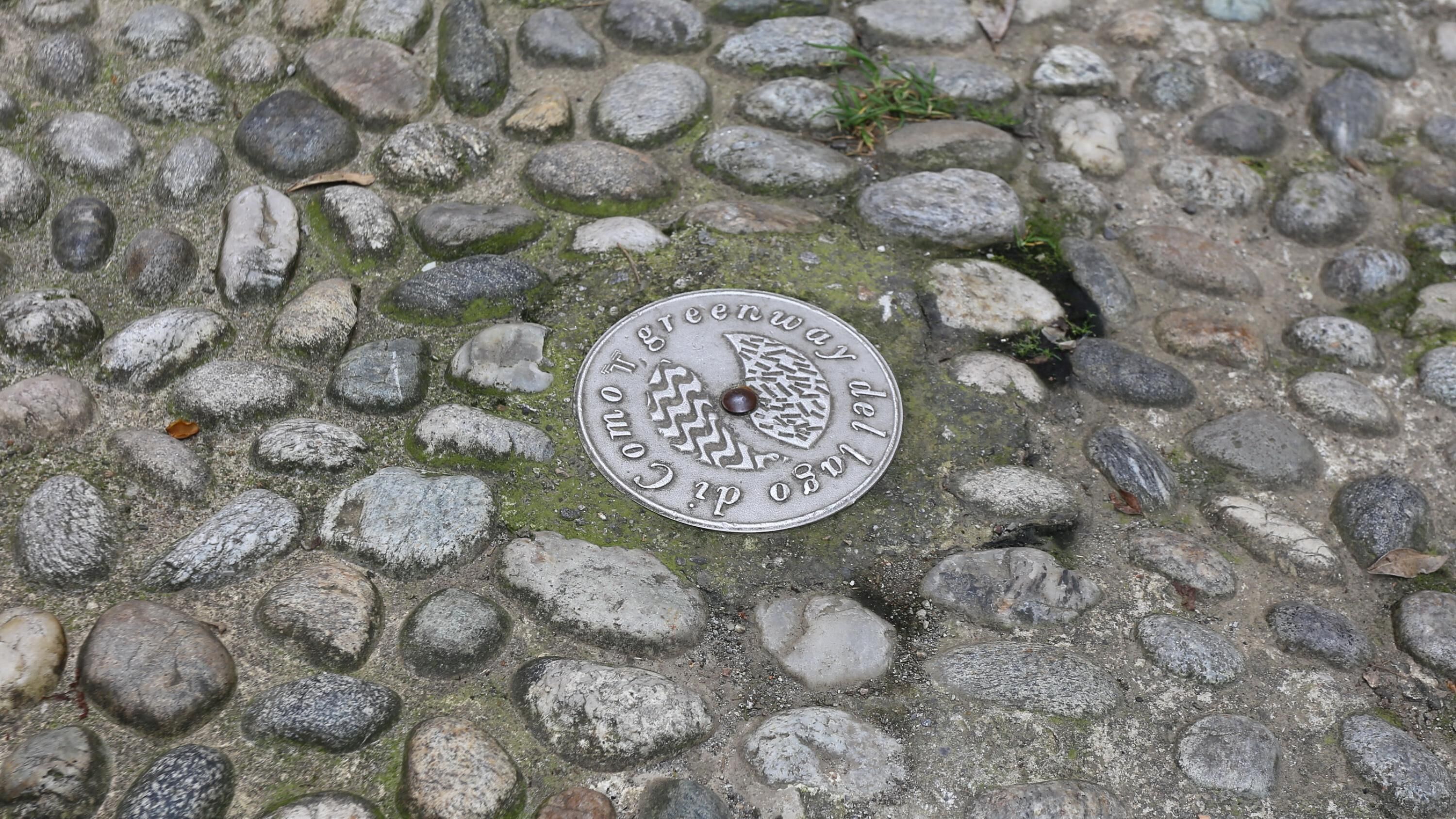 Una placa metálica con la inscripción "Greenway Trail" sobre una superficie de piedra.