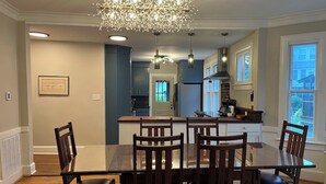 A modern kitchen with a central island, dark wooden chairs, and a chandelier.