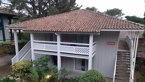 A small building with a tiled roof, a balcony, and a staircase leading to an upper level.