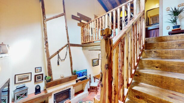 Una escalera de madera con diseño rústico, una chimenea y cuadros en las paredes.