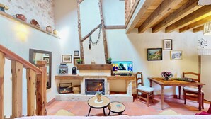 Una sala de estar acogedora con chimenea, vigas de madera y decoración rústica.