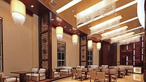Un hall d’hôtel doté d’espaces aménagés avec des sièges, de lustres et d’un sol à motifs.