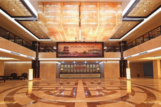 A spacious lobby with a high ceiling, a large central artwork, and a circular floor design.