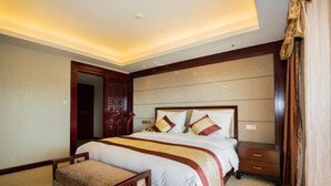 A hotel room with a large bed, a wooden nightstand, a bench, and a wardrobe. - XINFANDIAN Hotel (Ganzhou)