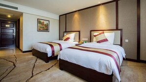 A hotel room with two beds, a large painting on the wall, and a door leading to another room. - XINFANDIAN Hotel (Ganzhou)
